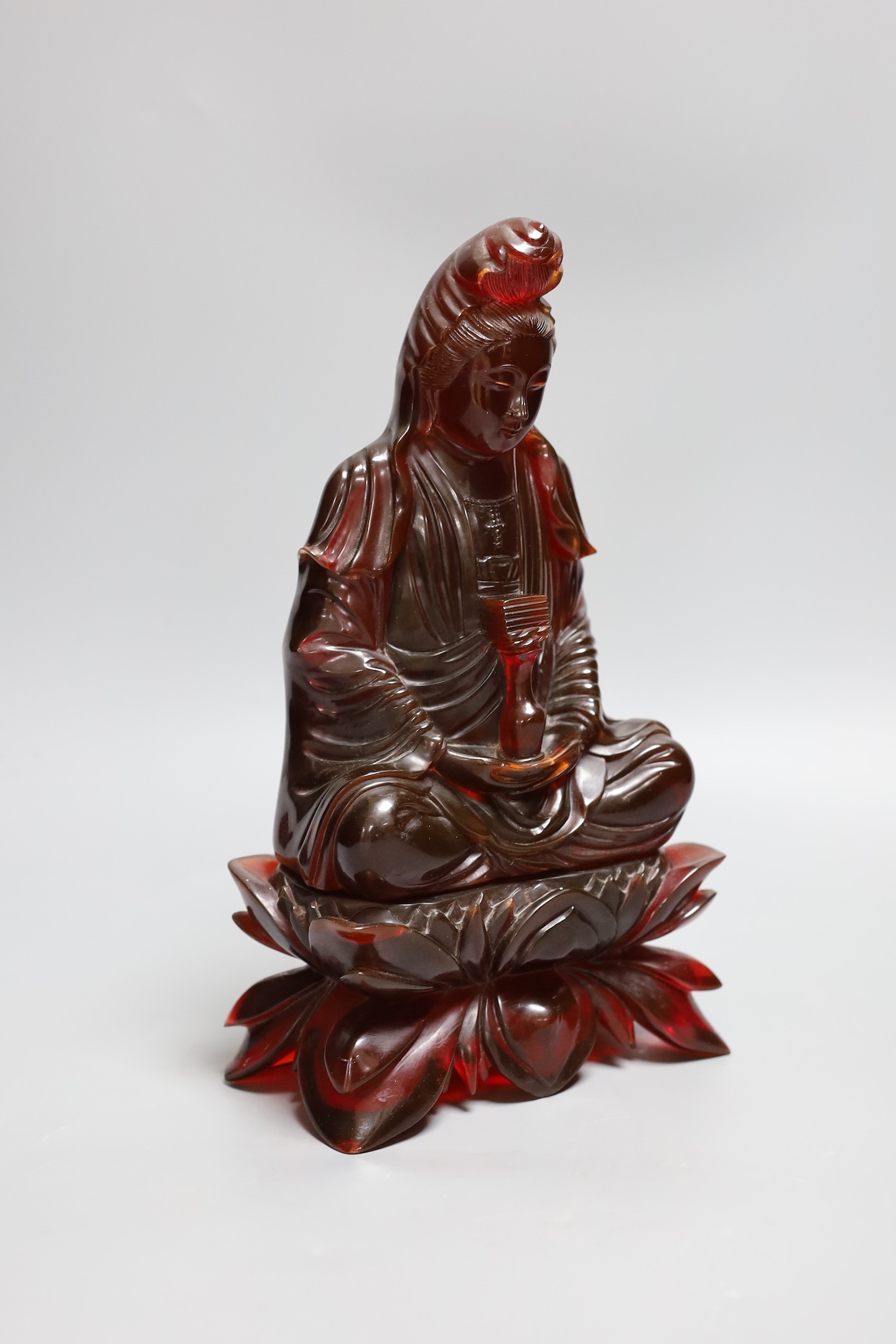 A Chinese ‘cherry amber’ phenolic seated figure of Guanyin, 29cms high